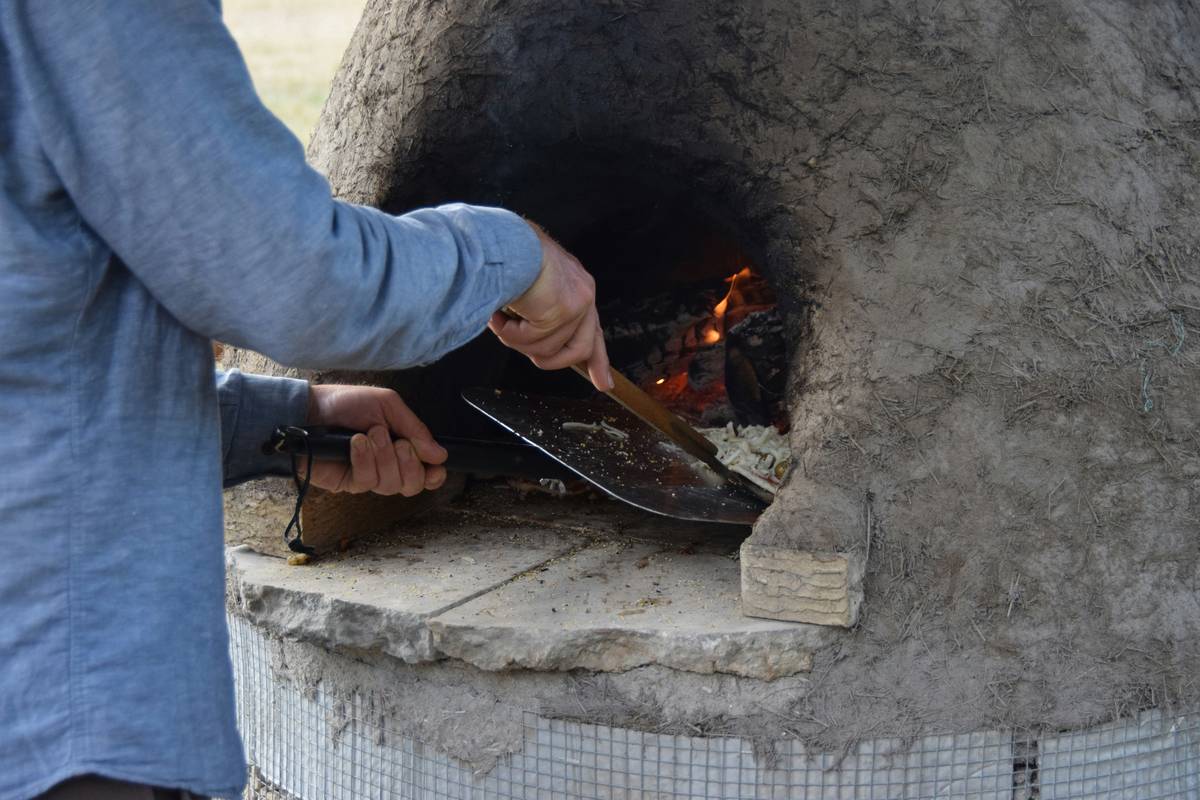 wood fired oven tools including a digital oven thermometer placed inside a brick pizza oven